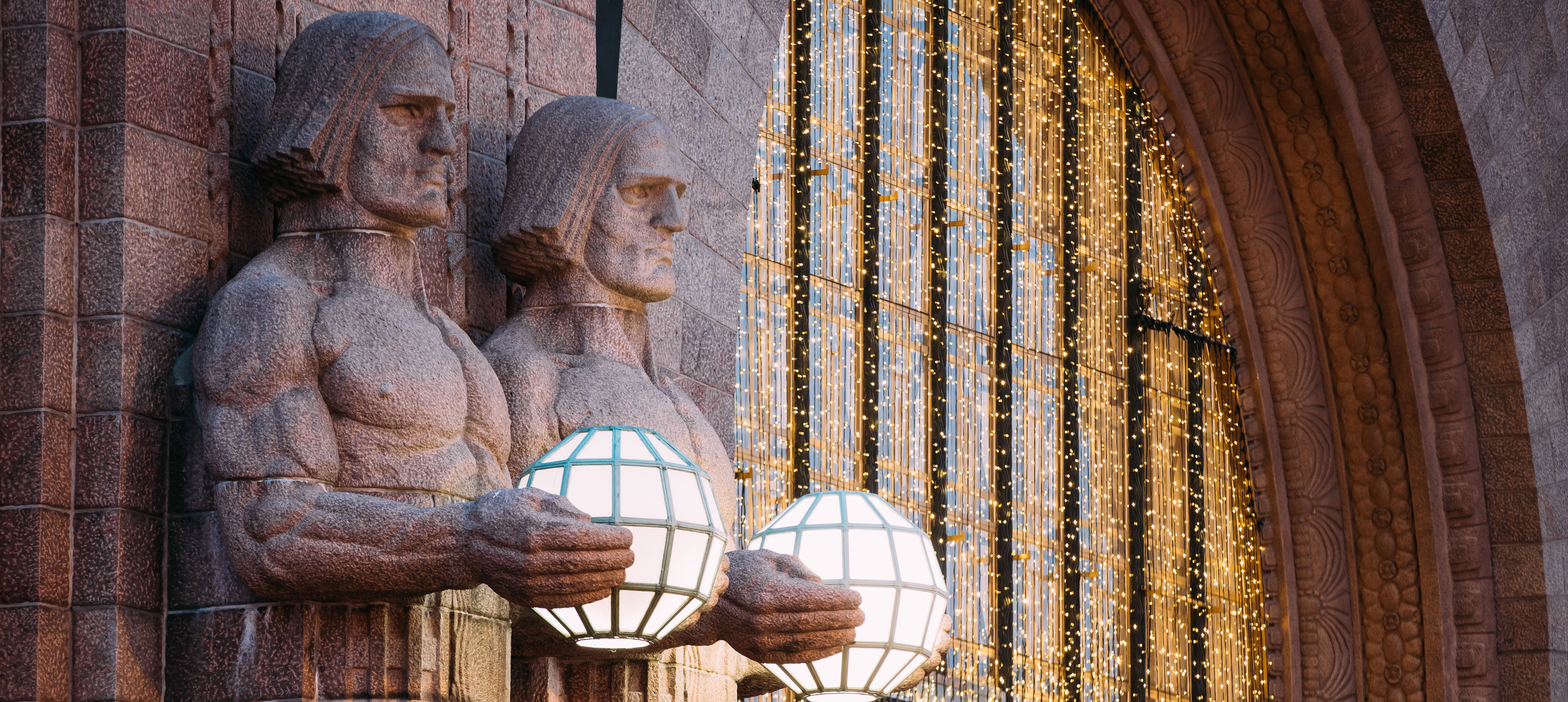 Beleuchtete Steinmänner am Eingang zu Helsinkis Hauptbahnhof

