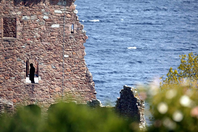 Man in Black in der Burgruine vor dem legendärsten See Schottlands