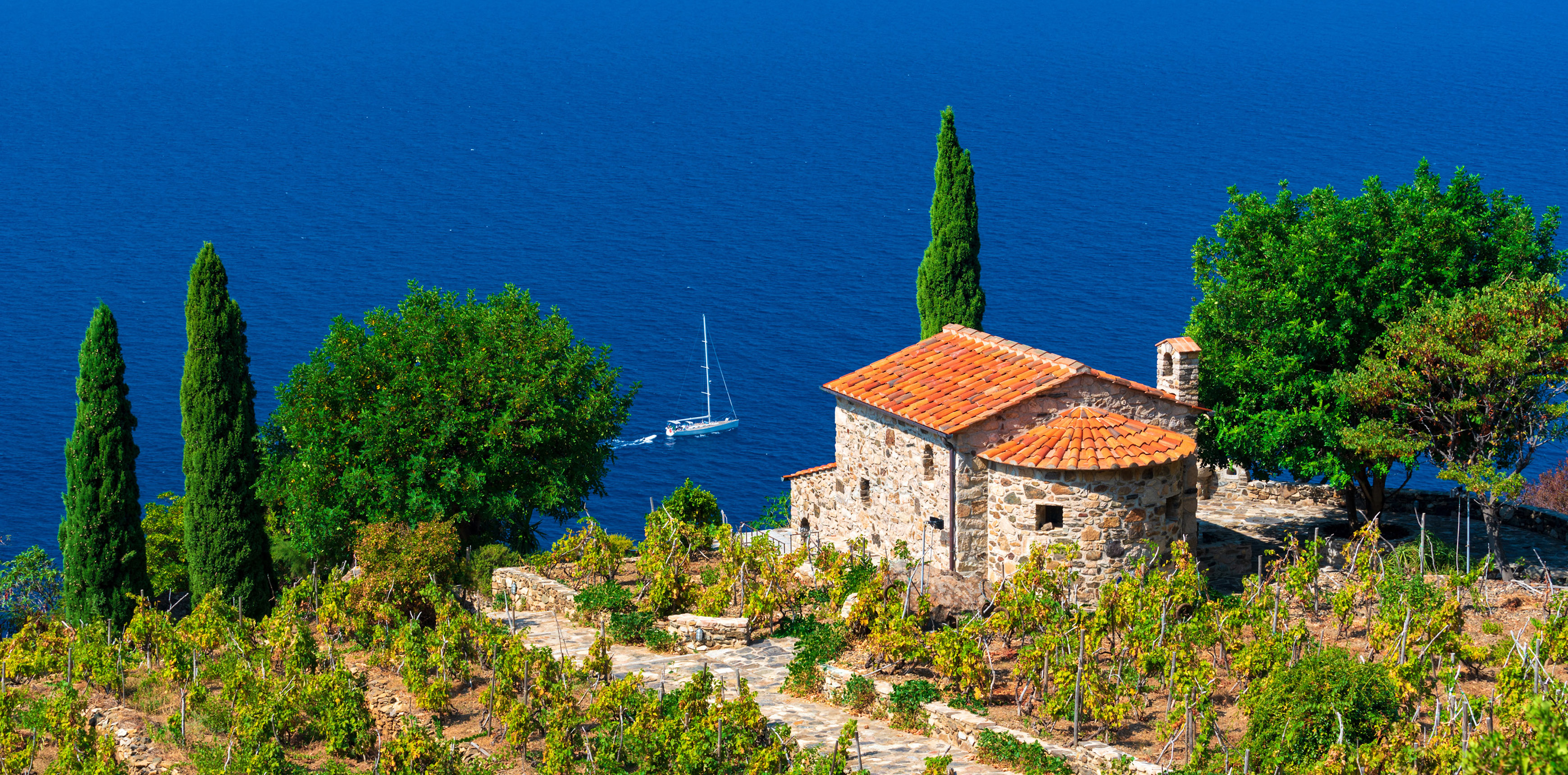 Kleine Kirche mit Blick auf das blaue Meer umgeben von Zypressen und Wein auf der Insel Elba in Italien